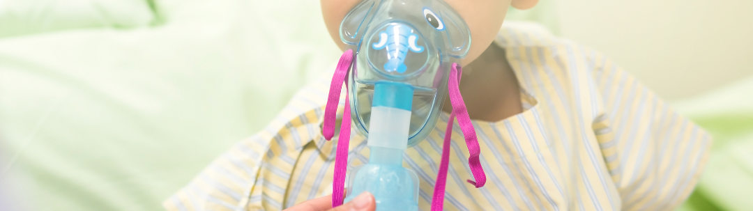 Sick young boy, 3 years old, inhale medication by inhalation mask to cure Respiratory Syncytial Virus (RSV) on hospital bed.