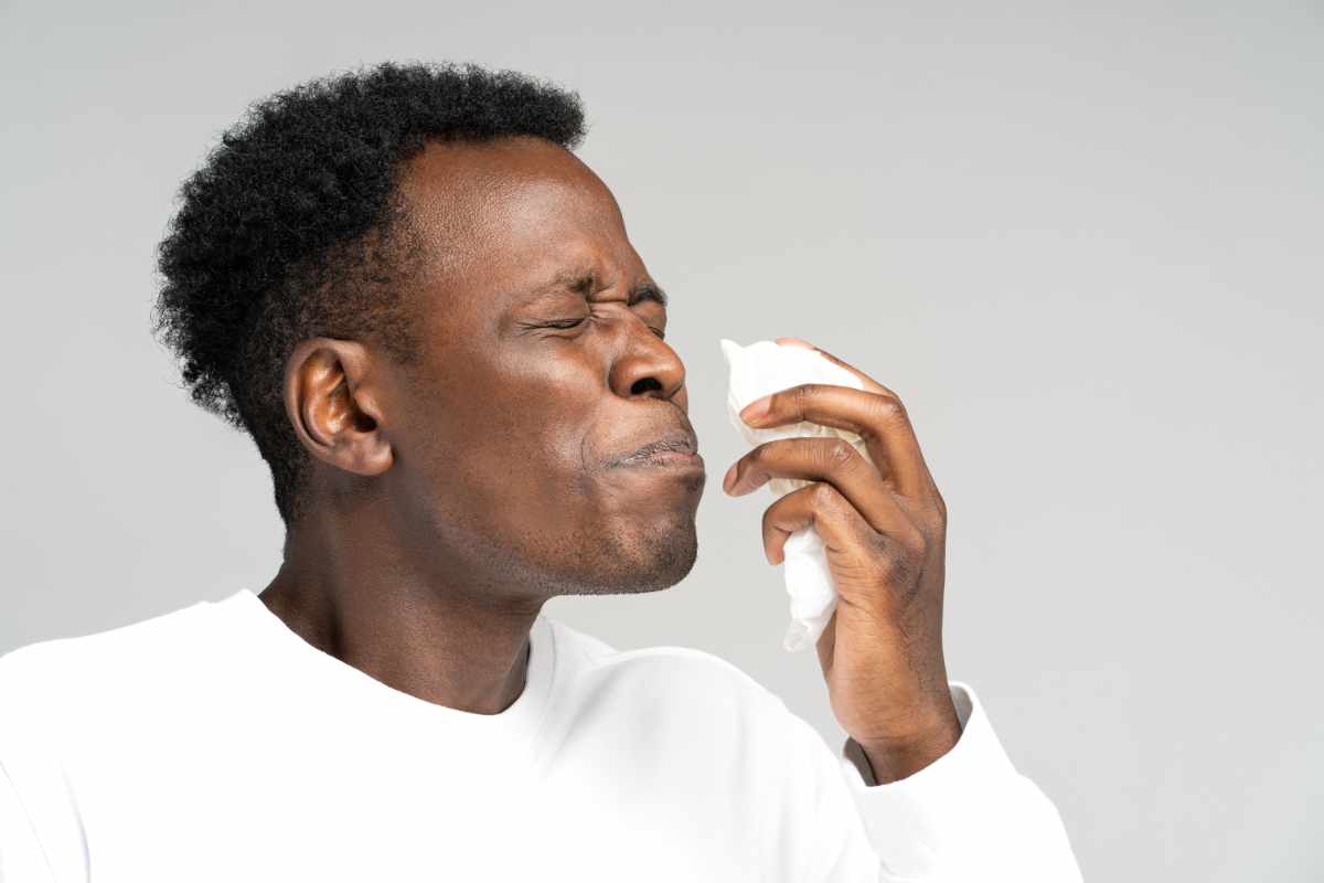 Black man ready to sneeze with a tissue near his nose.