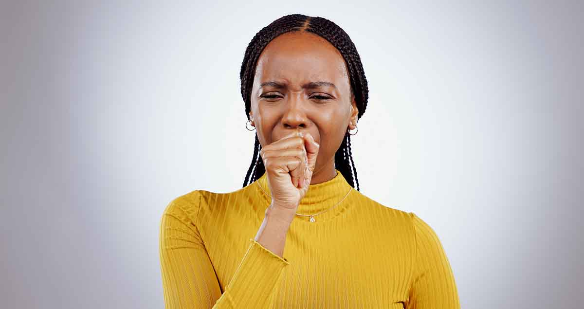 Black woman coughing wearing a yellow shirt