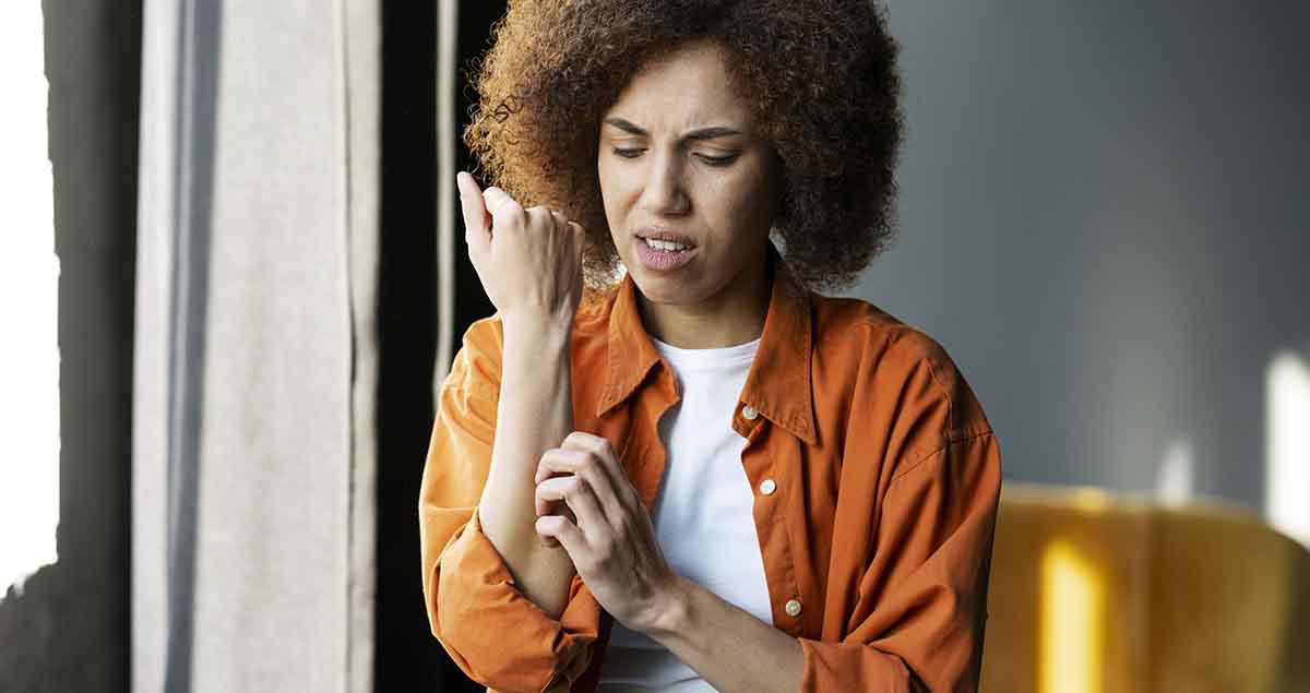 Multi-ethnic woman scratches her reddened hand due to itching.