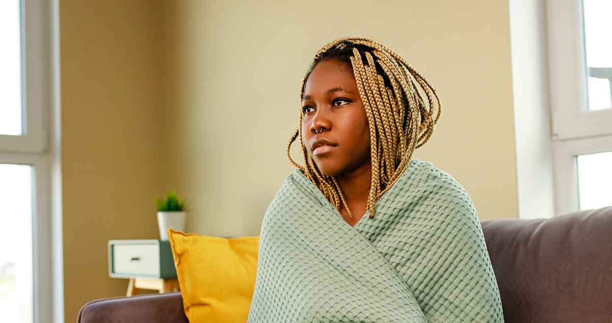 afro woman wrapped on blue blanket in living room.