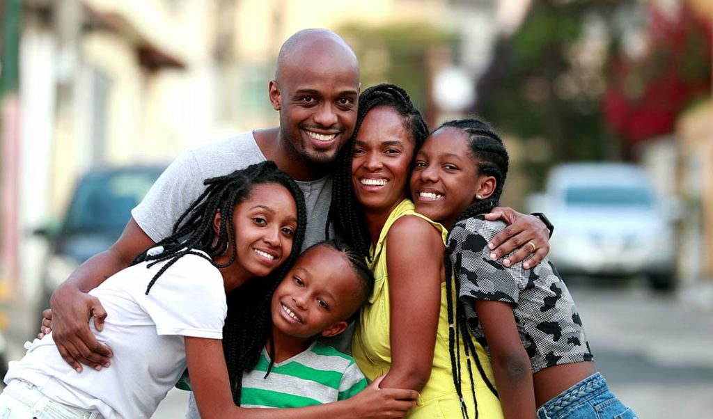 Happy African family portrait standing for photo outside. Cheerful black parents and children