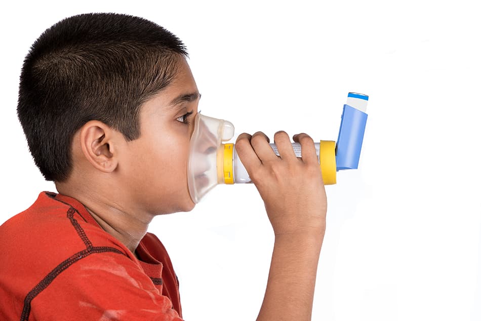 Young boy using a holding chamber and his asthma medication