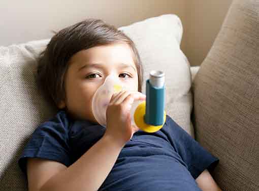 Photo of boy with a holding chamber sitting on a couch