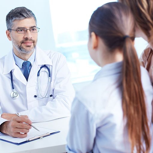 Doctor facing a parent and child taking notes