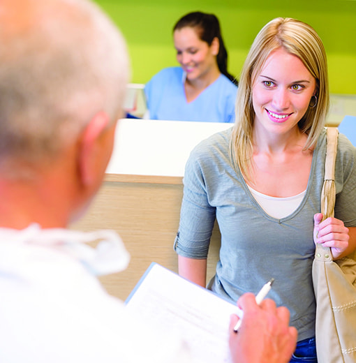 Photo of doctor greeting a young woman patient for an exam