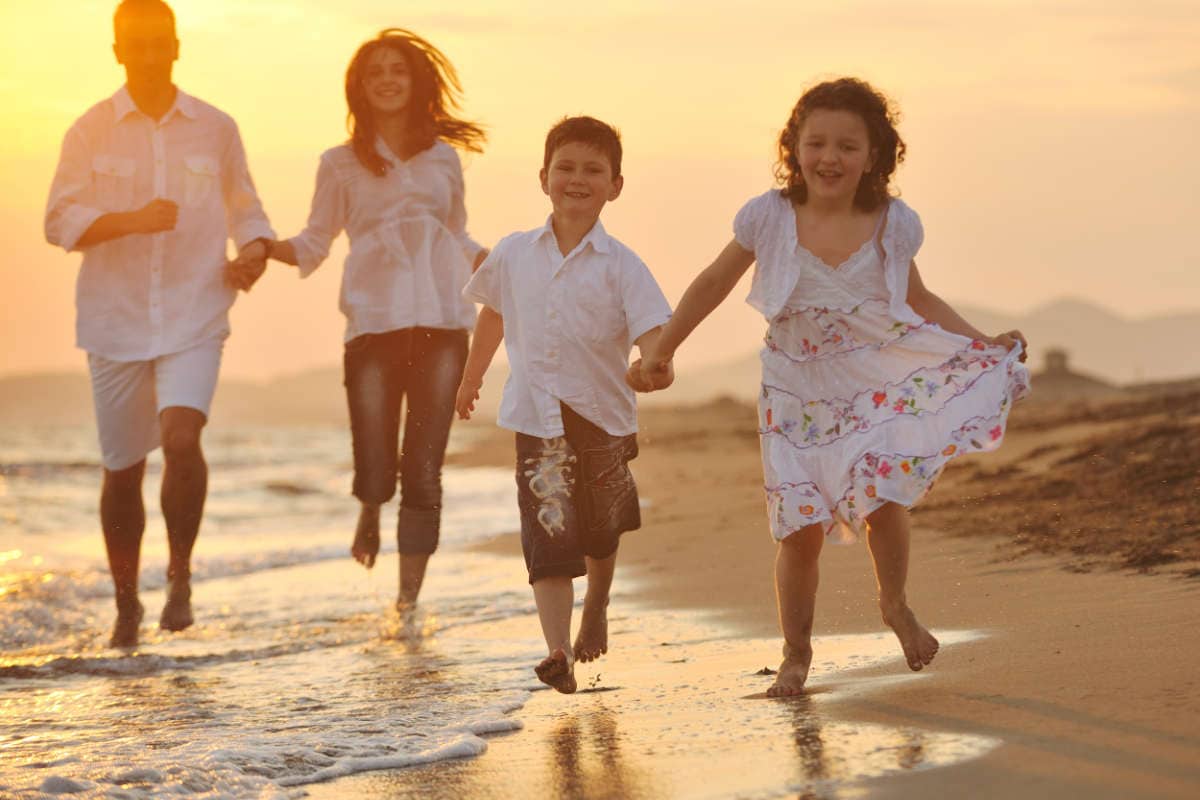 happy young family have fun on beach run and jump at sunset