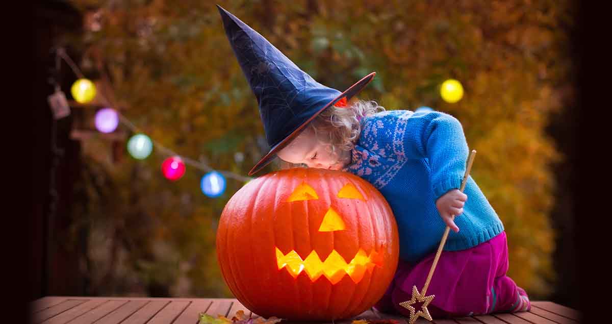 Little girl and boy carving pumpkin at Halloween. Dressed up children trick or treating. Kids trick or treat. Child in witch costume playing in autumn park. Toddler kid with jack-o-lantern.