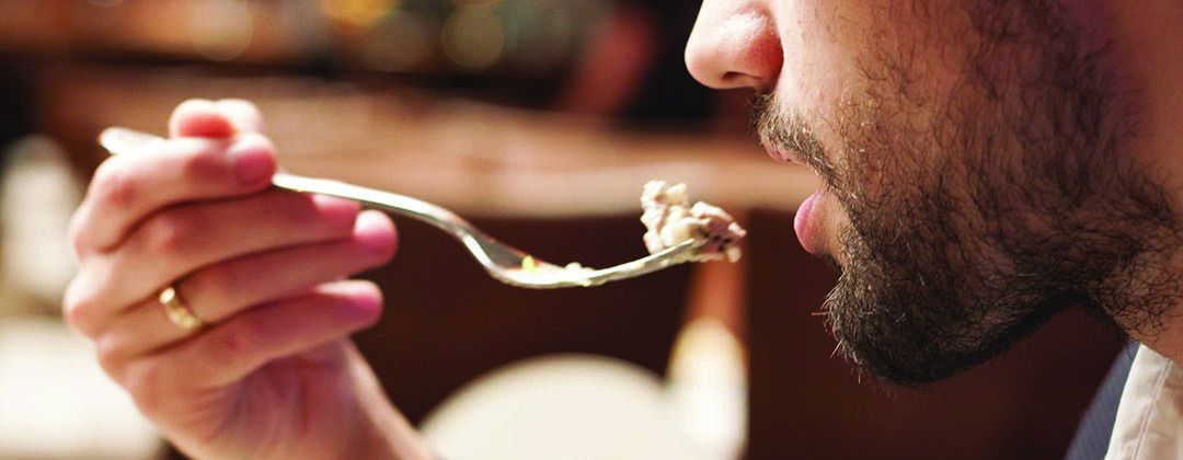 Photo of a man eating in a restaurant close-up view of food going into his mouth