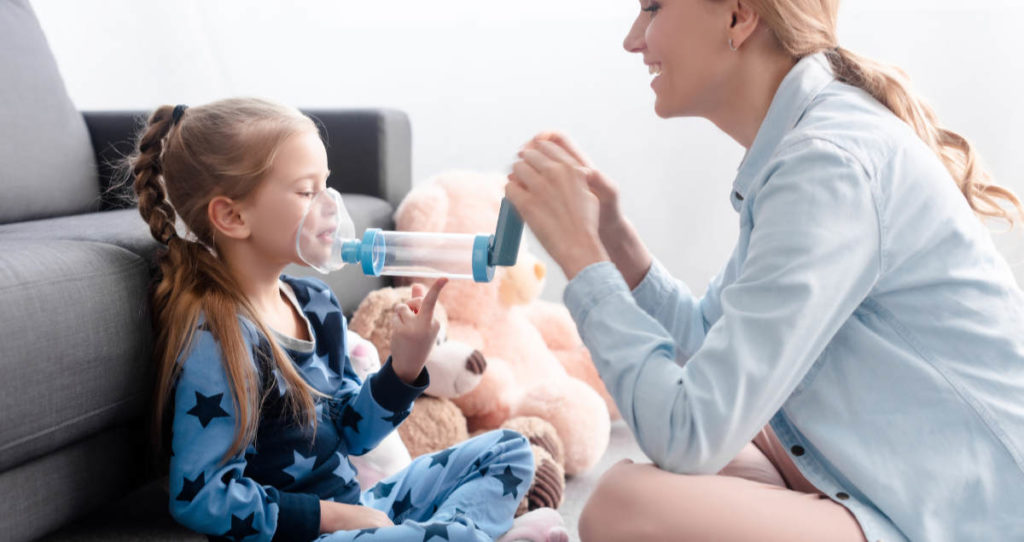 Mother with child helping with an inhaler.