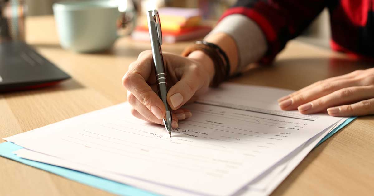 Woman filling out a paper form while sitting at a desk