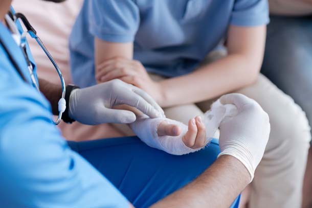 Close up of school nurse with latex gloves wrapping the wrist of a student with gauze