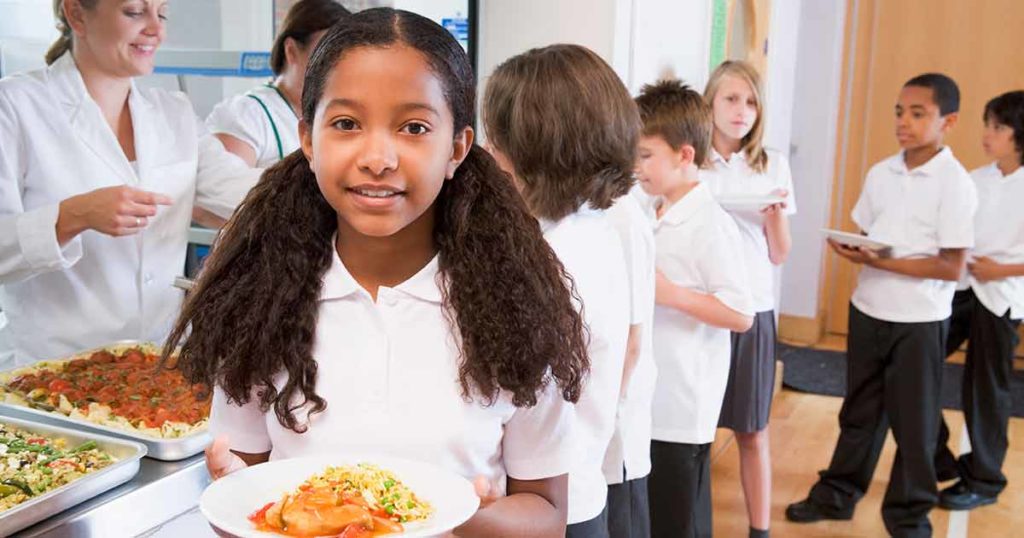 Children lined up at the school cafeteria getting their lunches