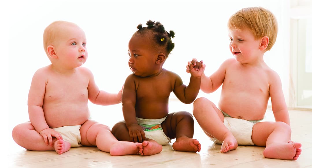 Photo of Three babies sitting indoors holding hands