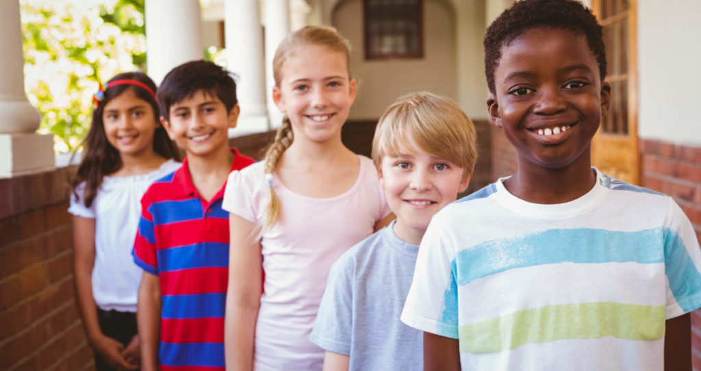 Photo of smiling little school kids in school corridor