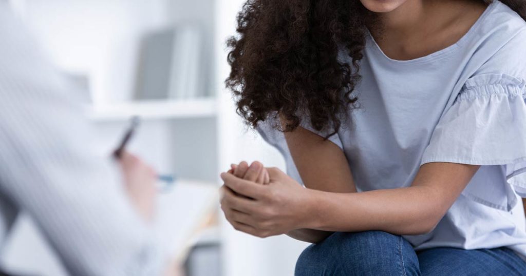 Woman sitting down and discussing feedback to a drug development clinician