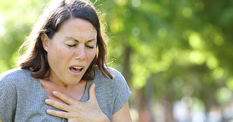 Woman in the park clutching her chest and gasping for air and is in distress