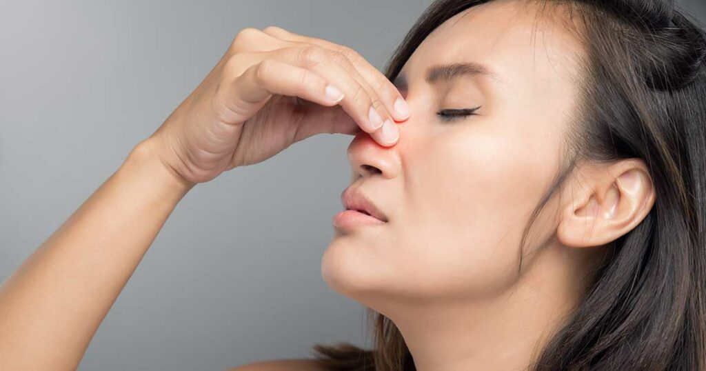 Woman holding her nose because her sinuses are in a lot of pain.