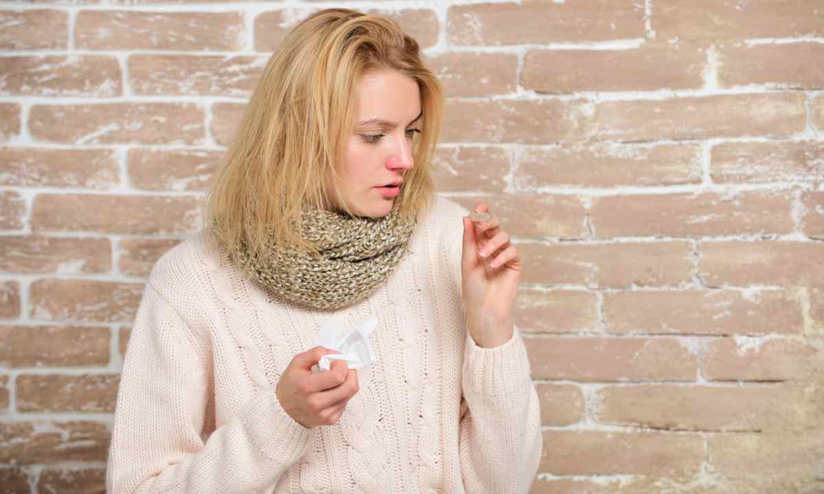 Woman with red and swollen nose is looking at her temperature