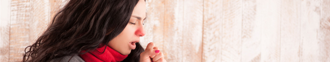 Side view image of young sick woman with scarf on her neck sitting in bed and coughing from whooping cough with her country house in the background