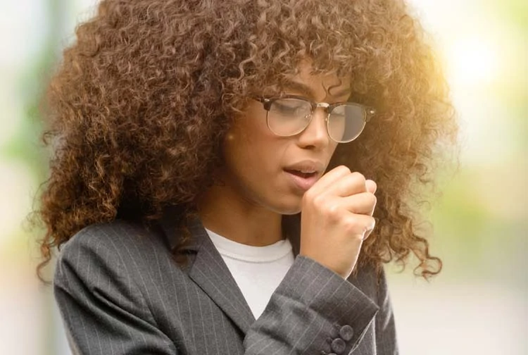 Image of Black woman coughing into her hand