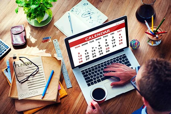 Image of man looking at laptop with calendar on it