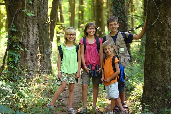 Kids of various ages in the park hiking during a hot summer day.