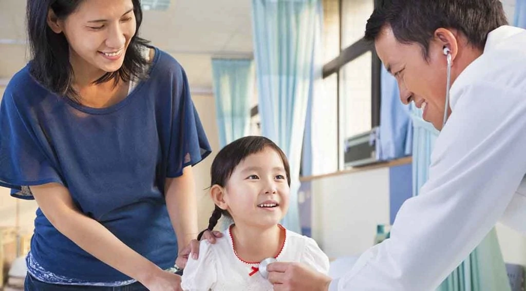 Pediatrician examining little girl , her mother beside her