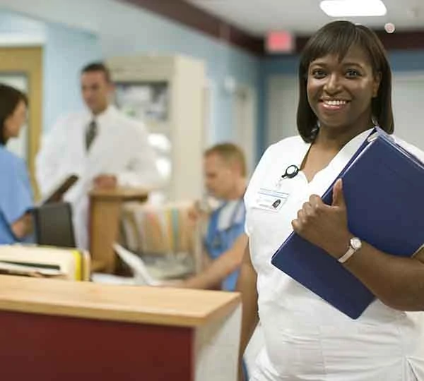 Photo of Female nurse in hospital reception area, smiling, portrait