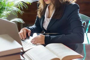 Woman at computer with book nearby. She